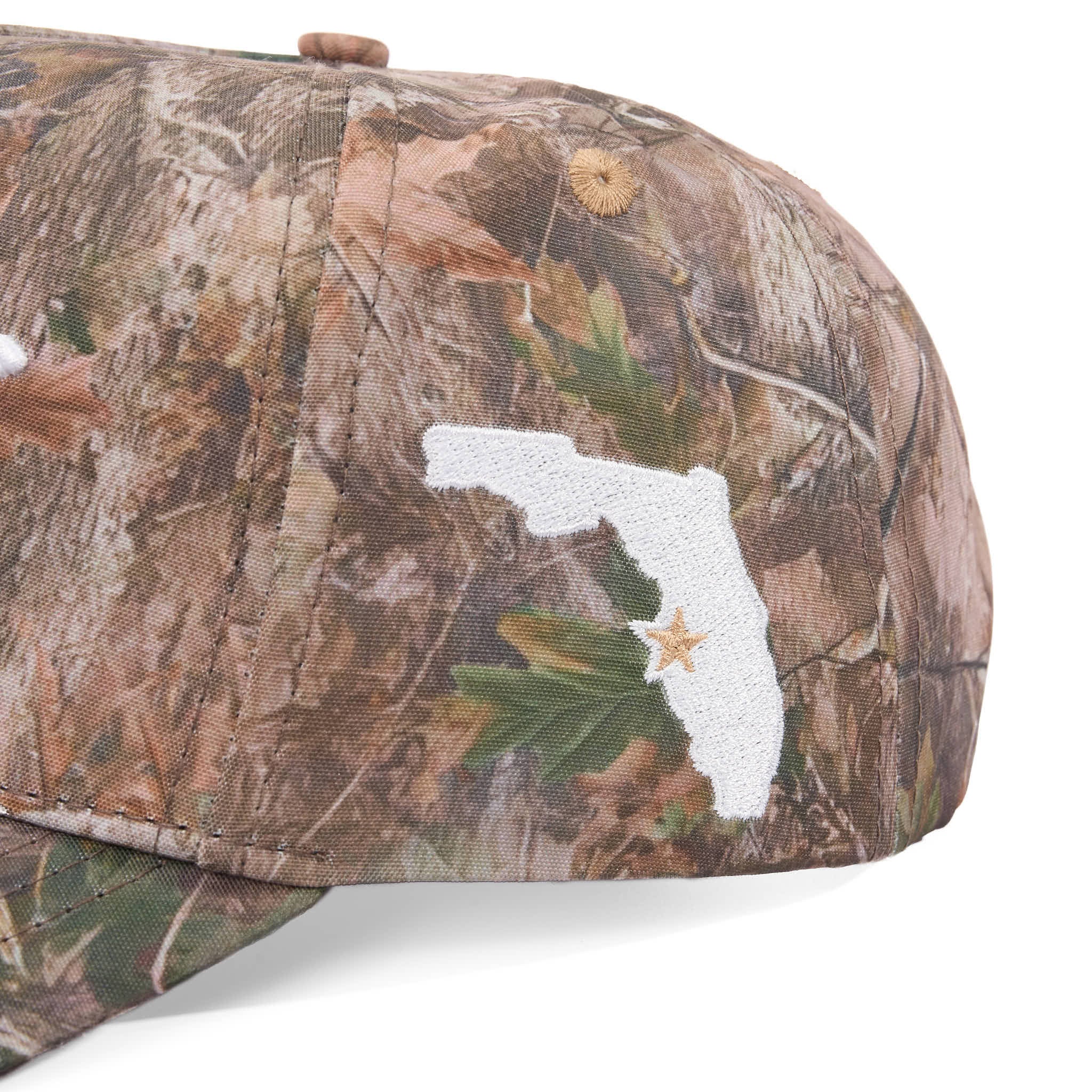 Camouflage cap with a white embroidered design on a white background